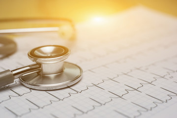 doctor workplace with a stethoscope at wooden table,Cardiogram chart with medical stethoscope and on table closeup,for Surgeon doctor Medical heart,selective focus,vintage color.morning light