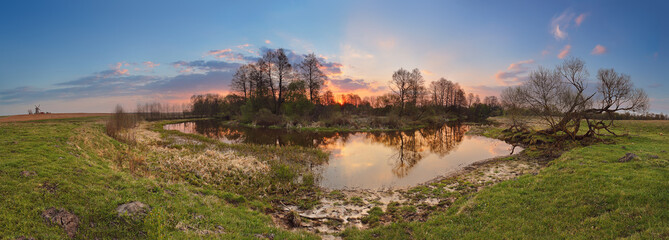 Fototapeta na wymiar Spring sunset panorama. Small river in evening