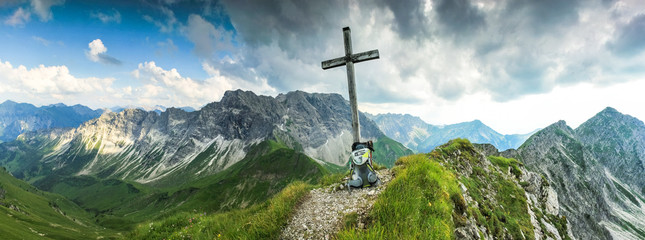 Wooden summit cross and summer colors in mountains. Panoramic view.