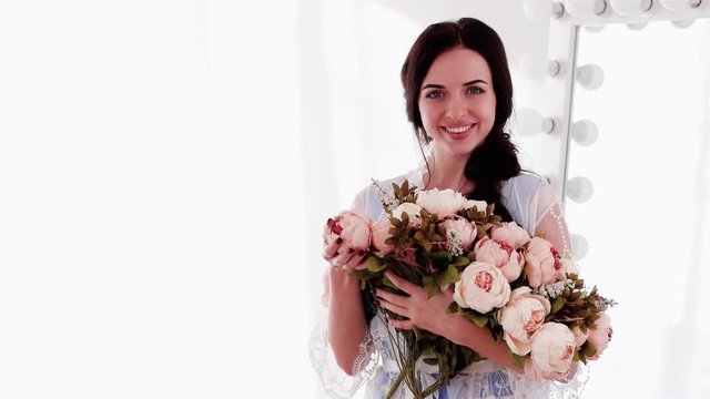 happy smiling woman holding huge pink and beige bouquet of peonies, long-haired girl in white fond of big bouquet of flowers, tenderness in photo, beautiful lady posing in spring photo session