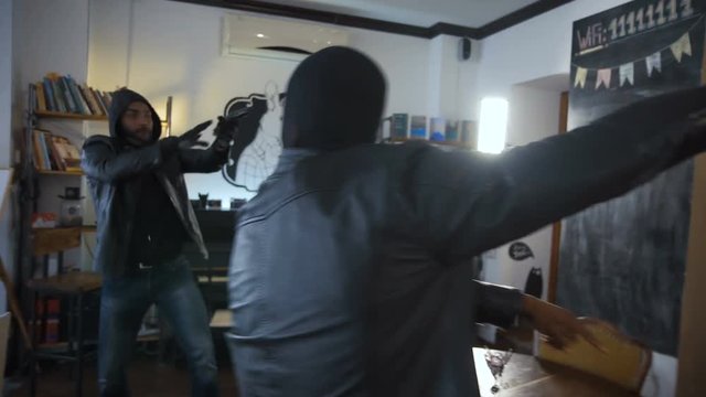 African and Caucasian people walking into the shop and aiming to the assistant with guns. 4K Hand held shot