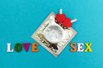 Condom and red hearts on a blue background, the inscription "love sex"