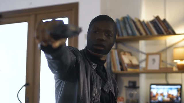 The blurred African robber aiming with the gun to the camera.