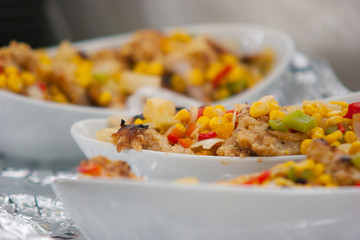 Fish filet served with sweet corn, bell peppers, and chopped tomato