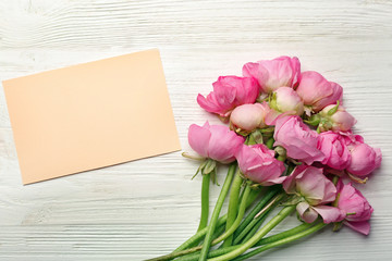 Beautiful ranunculus flowers and card on light wooden background