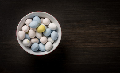 Pastel Easter Eggs in bowl on wooden background