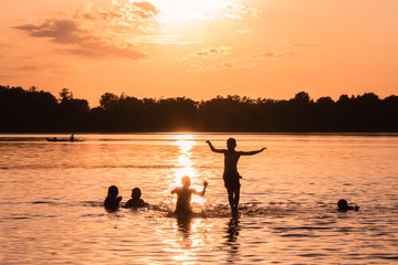 Family and friends are having fun under sunset over a lake
