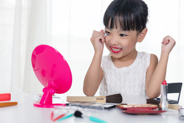 Asian Chinese little girl applying makeup with cosmetics