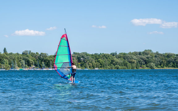 A young man is windsurfing in a lake