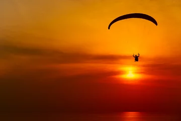 Fototapete Luftsport Gleitschirm-Silhouette vor dem Hintergrund des Sonnenuntergangshimmels