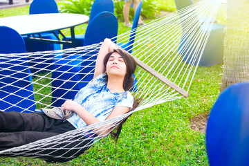 Teenage girl resting in hammock at resort, eyes closed