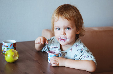 Cute little boy eating a yoghurt.