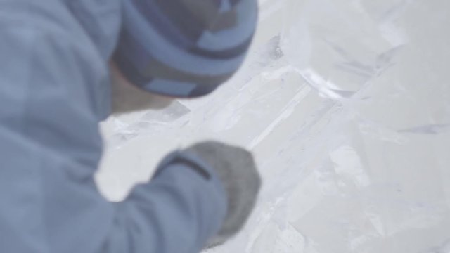Master Scraper Performs A Movement Across The Ice To Create An Ice Sculpture. Master using Special Tool To Grind Down Form Ice Pieces. Ice Compositions Performs Notches And Grooves In The Piece Of