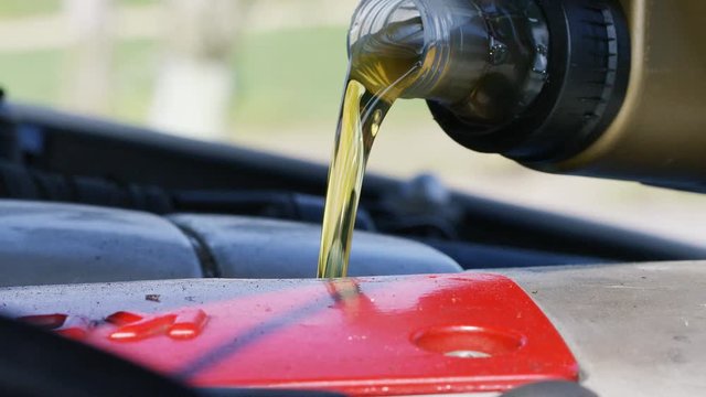 4K Close up of fresh oil being poured into a vehicle, in slow motion 