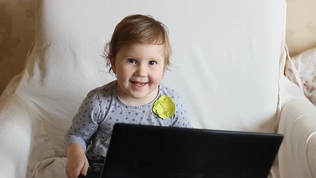 Beautiful girl is sitting at the laptop and is studying the internet.