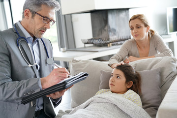 Doctor visiting sick little girl at her house