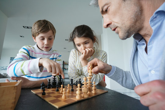 Family playing chess game at home