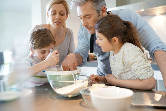 Family baking cake together in home kitchen