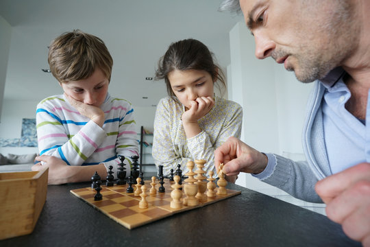Family playing chess game at home