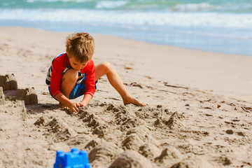 little boy play with sand on summer beach