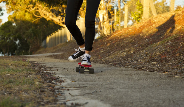 Young woman skate boarding at sunset