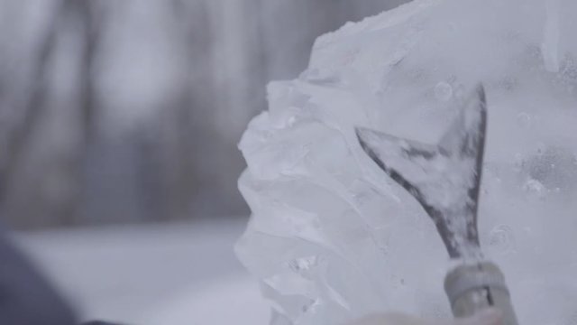 Master Scraper Performs A Movement Across The Ice To Create An Ice Sculpture. Master using Special Tool To Grind Down Form Ice Pieces. Ice Compositions Performs Notches And Grooves In The Piece Of
