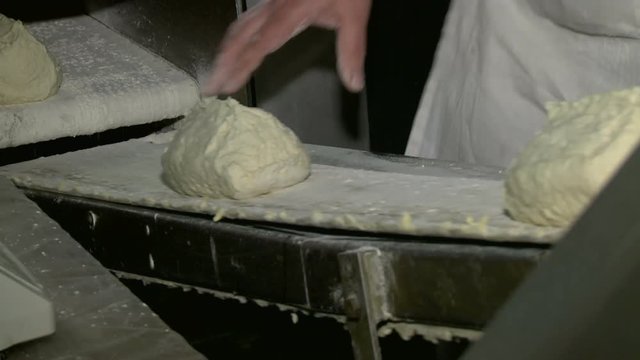 Billets of bread in the form of dough move along the conveyor belt