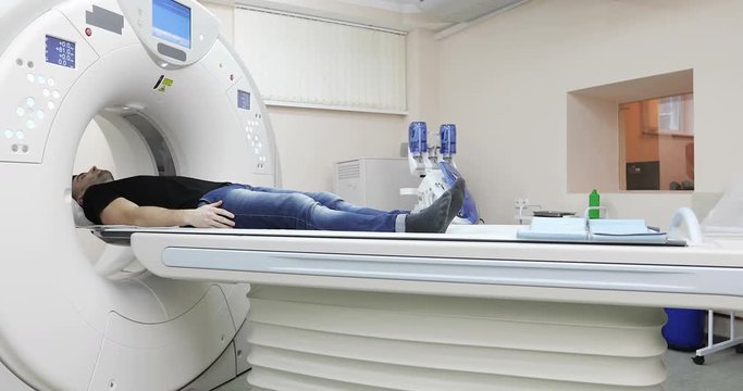 4K Young caucasian male gets scanned by magnetic resonance imaging scanner in modern hospital.