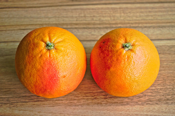 Two red grapefruits on a wooden table