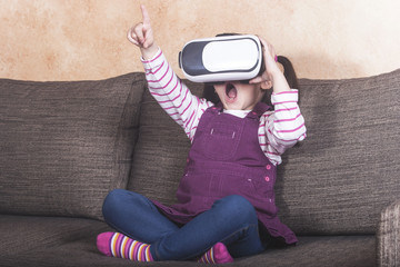Astonished little girl experiencing virtual reality at home