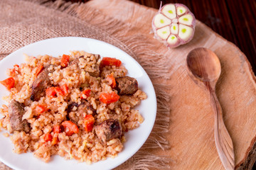 Pilaf on the white plate on a wooden background. Top view. Copy space. Rustic style