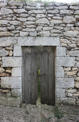 Old wooden door, abandoned building with damaged stone wall