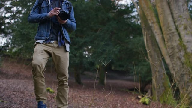4K Photographer takes a photo as he enjoys the view in the forest, in slow motion 