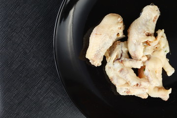 Boiled chicken feet on black color plate represent the asian food and thai cuisine concept related idea.