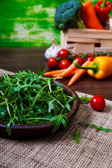 Arugula leaves in bowl. Fresh salad. Carrot, pepper and cherry tomatoes. Natural raw vegetables. Organic bio food on rustic wooden table.
