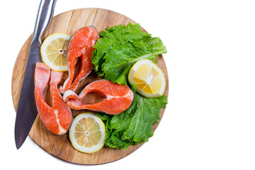 Raw salmon steaks with lemon and green salad. Isolated
