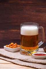 Glass of beer. Mexican salsa nuts. Appetizer with sweet salsa or chilli sauce. Mug or pint of ale. On rustic wooden background.