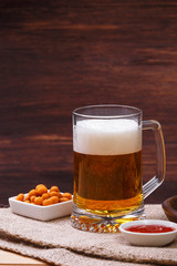 Glass of beer. Mexican salsa nuts. Appetizer with sweet salsa or chilli sauce. Mug or pint of ale. On rustic wooden background.