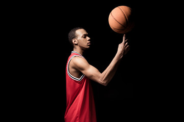 Side view of athletic basketball ball holding ball on finger