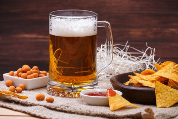 Glass of beer. Nachos chips. Tortilla snack. Mexican salsa nuts. Appetizer with sweet salsa or chilli sauce. Mug or pint of ale. On rustic wooden background.
