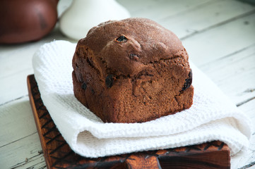 Rye bread with dry fruits filling on a wooden board with white towel. White background.