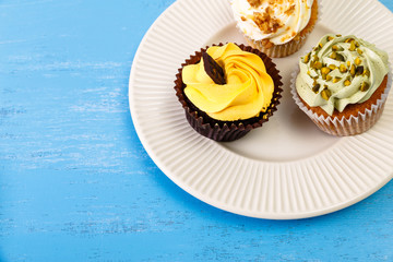 Cupcakes with buttercream. Sweet cake with pistachio nuts cream and small chocolate bar. Dessert with topping. Wooden rustic background.
