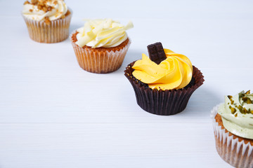 Cupcakes with buttercream. Sweet cake with pistachio cream and small chocolate bar. Dessert on white wooden background.