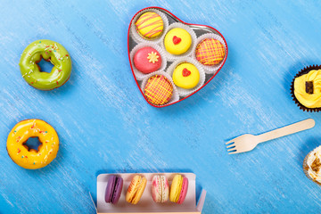 Macaroons, Glazed donuts and Cupcakes. Sweet dessert. Cakes with nuts cream. Almond macaron cookies in heart-shaped box.