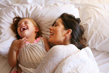 Mother and daughter laying in bed.