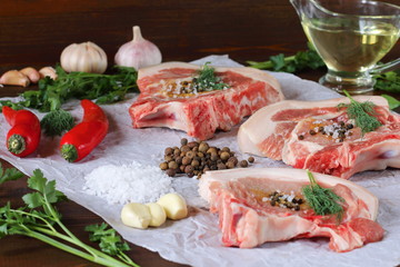 Spices and pieces of raw pork lie on the table for cooking.