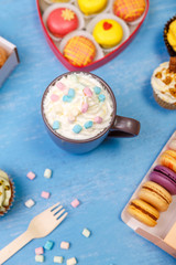 Macaroons, cupcakes and donuts. Mug with whipped cream and marshmallows. Almond macaron cookies. Sweet dessert.