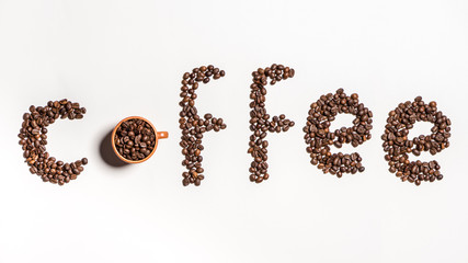 Top view of word coffee made from coffee beans in cup and on white