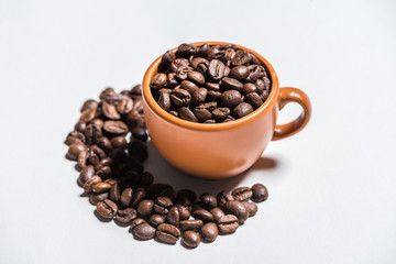 Close-up view of roasted coffee beans in cup on white