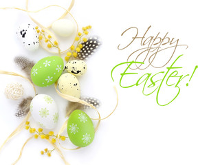 Easter eggs and mimosa flowers on white background with space for your text. Top view.